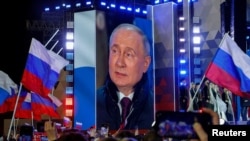 Руският президент Владимир Путин се появява на екран на сцената, докато присъства на митинг, отбелязващ 10-ата годишнина от незаконното анексиране на украинския Крим от Русия, в Москва на 18 март.