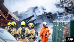 Pompierii olandezi lângă ruinele fumegânde după stingerea incendiului, la Haga, pe 7 decembrie.