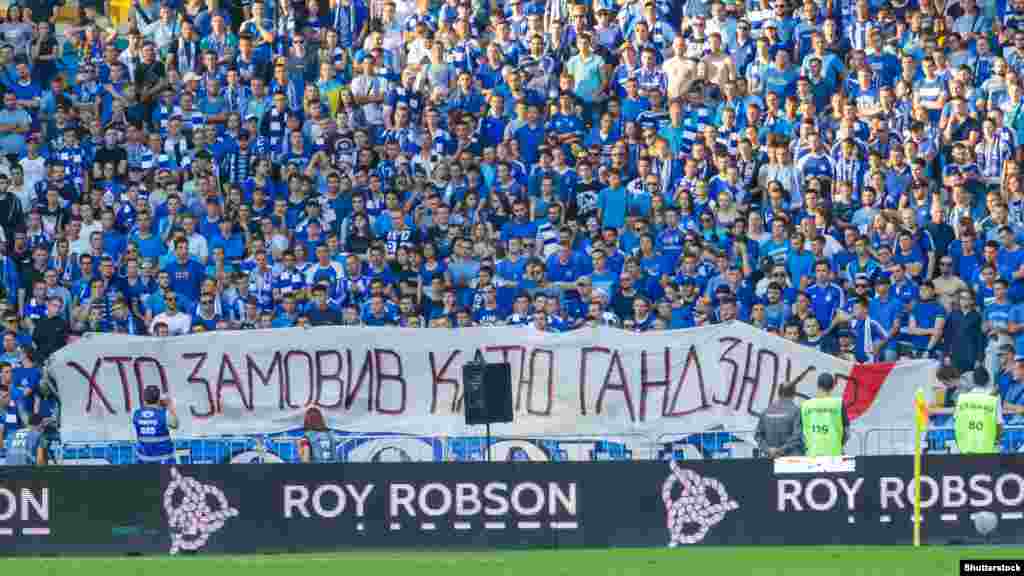 Напис на полотні &laquo;Хто замовив Катю Гандзюк?&raquo;, яке розгорнули фанати команди &laquo;Динамо&raquo; під час футбольного матчу української Прем'єр-ліги. Київ, 3 серпня 2018 року