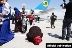 Сириядан алып келинген аял учактан түшүп жерди өөп жатат. Ташкент, 2019-жыл.