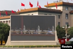 На экране з трансьляцыяй параду ў Пэкіне на трыбуне сядзяць Аляксандар Лукашэнка, прэзыдэнт Кубы Мігель Дыяс-Канэль Бэрмудэс і прэм’ер-міністар Пакістану Шагбаз Шарыф, 3 верасня 2025 году