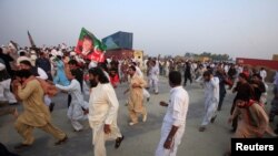 Supporters of Pakistani opposition leader Imran Khan run from tear gas as clashes begin between police and protesters in Swabi on October 31.