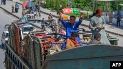 هېواد ته ستنېدونکی یو کډوال له پېښوره د روانېدو پر مهال د افغانستان بیرغ رپوي - د اپرېل څلورمې انځور.