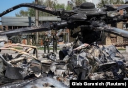 Trupele ucrainene inspectează un elicopter rus distrus la aerodromul Hostomel, din regiunea Kievului, 5 mai 2022.