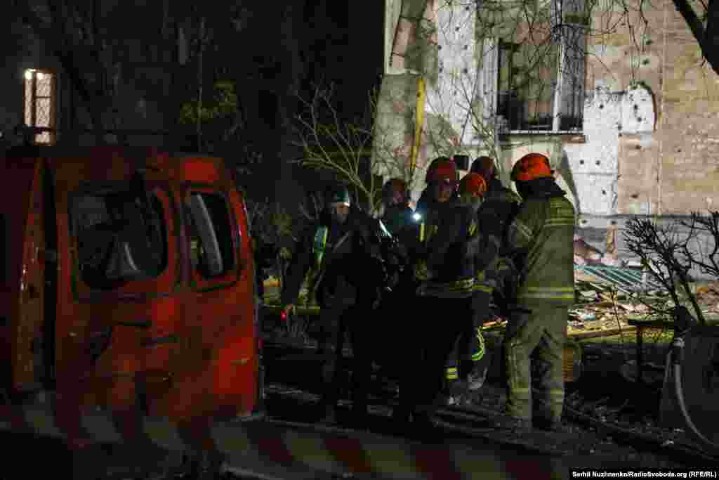 Рятувальники несуть тіло загиблої людини з житлового будинку в одному з районів Києва, який опинився під обстрілом російських військ. Київ, 29 листопада 2025 року