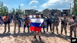 In this image taken from a video released by the Prigozhin Press Service on May 20, Yevgeny Prigozhin, the head of the Wagner Group, holds a Russian national flag in front of his soldiers in Bakhmut.