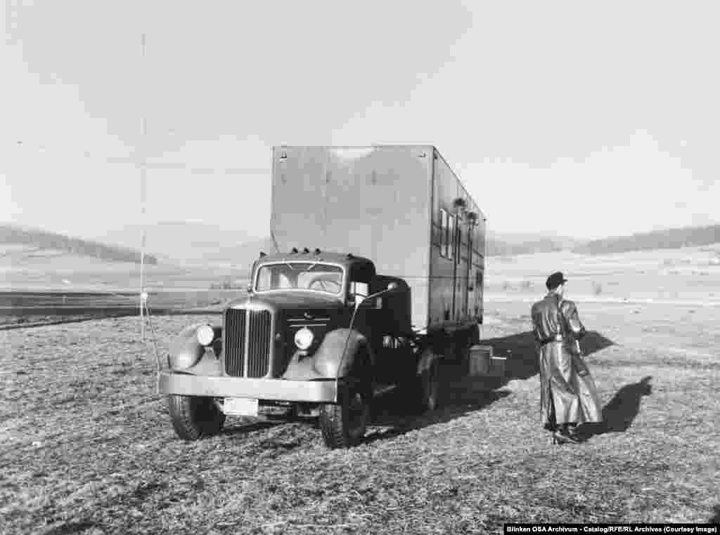 Узброены ахоўнік патрулюе грузавік зь сярэдняхвалевым радыёперадатчыкам у Заходняй Нямеччыне недалёка ад мяжы з Чэхаславаччынай у 1955 годзе.Калі камуністычныя дзяржавы пачалі глушыць перадачы РСЭ/РС, Радыё Свабодная Эўропа разгарнула дзясяткі мабільных перадавальных станцыяў, такіх як тая, што на фота. Яны маглі працаваць паблізу «жалезнай заслоны».