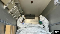 Представники Міжнародного комітету Червоного Хреста перевіряють мішки з останками військовослужбовців під час обміну тілами, серпень 2024 року