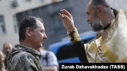 Un preot, în catedrala din Moscova, îl binecuvântează pe prezumtivul criminal de război Igor Ghirkin (Strelkov), fost comandant rus în Donețk și ofițer FSB acuzat că ar fi fost la originea doborârii avionului de pasageri MH17 al Malaysia Airlines, 10 iulie, 2014.