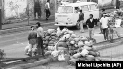 სასწრაფო დახმარების მანქანა ქვიშის ტომრების საკონტროლო-გამშვებ პუნქტებს გადის, რათა თეირანის ქუჩაში შეტაკების დროს დაჭრილი აიყვანოს. 1979 წლის 10 თებერვალი. არმიას, საჰაერო ძალების კადეტებსა და ხომეინის მიმდევრებს შორის შეტაკებებს 60 ადამიანზე მეტი შეეწირა, ასობით მოქალაქე კი დაშავდა.