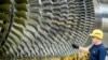 A worker stands next to a turbine at the Siemens Gas Turbine Plant in Berlin.