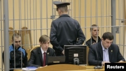 Dzmitry Kanavalau (left) and Uladzislau Kavalyou sit in a cage before court hearings in Minsk in September 2011.