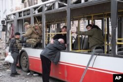 Мъж плаче, облегнат на автобус, ударен от руска балистична ракета в Суми, 13 април 2025 г.