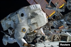 Astronautul NASA Terry Virts, inginer de zbor al Expediției 42, lucrează pentru a finaliza o sarcină de rutare a cablurilor în apropierea portului din față al modulului Harmony de pe Stația Spațială Internațională, 21 februarie 2015.