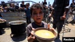Copil palestinian care așteaptă să primească mâncare. 24 iulie 2025