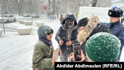 Активистка Акторгын Аккенжебаласы разговаривает с представителям власти, который прерывает ее пикет в Алматы, 22 января 2025 г.
