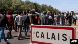 Мигранты направляются по трассе к портовому городу Кале, 17 июня 2015 года.