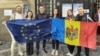 شهروندان مولداوی در رومانی پرچم‌های اروپا و مولداوی را در یک حوزه رأی‌گیری مهاجران در بخارست در دست دارند