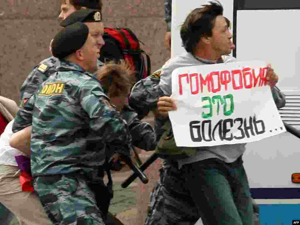 Police arrest a gay-rights activist as he holds a poster reading "Homophobia Is A Disease" during an unsanctioned gay-pride rally in St. Petersburg on June 25, 2011.