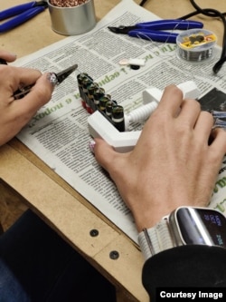 Žena u radionici u Lavovu obljepljuje baterije iz jednokratnih e-cigareta poslane iz Leedsa u snop koji će biti smješten u prenosivi punjač.