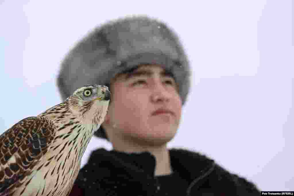 Ловец с ловна птица на на рамото наблюдава състезанието.