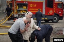 Спасатели помогают раненой пожилой женщине после российского ракетного удара по Сумам 24 марта 2025 года