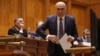 Premierul Ilie Bolojan se pregătește să citească unul dintre cele cinci discursuri pentru proiectele prin care guvernul și-a asumat răspunderea în Parlament. 