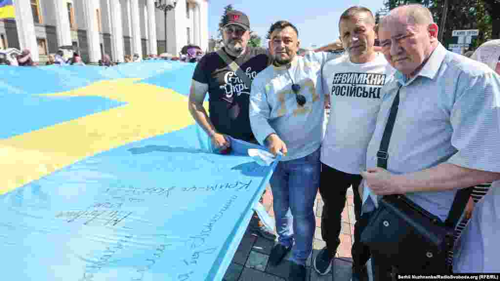 Aralarında İlmi Umerov ve Volodımır Baluh da olğan qırımlılar qırımtatar bayrağını Ukrayina Yuqarı Radasınıñ binasına taşıy, 2021 senesi iyülniñ 15-i