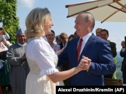 Австрия тышкы иштер министри Карин Кнайсль жана Орусия президенти Владимир Путин министрдин тоюнда бийлеп жатышат.