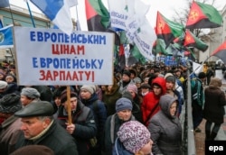 A man carries a placard reading "European salary for European prices" during an antigovernment rally in front of parliament in Kyiv on December 8.