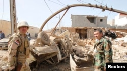 Ирактык аскерлер жанкечти жардырган автомобилдин жанында турушат. Киркуктун батыш ныптасындагы Дебис шаарчасы. 11-март, 2013