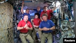 Comandantul Terry Virts de la NASA (stânga) predă comanda Stației Spațiale Internaționale cosmonautului Gennady Padalka (dreapta) de la Agenția Spațială Federală Rusă, 10 iunie 2015.