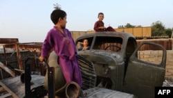 Мазари-Шарифте советтик армиядан калган эски машиненин үстүндө ойноп жаткан балдар. 