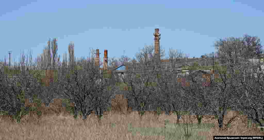 Bazarçıq (Poçtovoye) köyünde arqasındaki şarap zavodınıñ boruları ile terk etilgen alma bağçası. Dneprden kelgen kişilerge ait zavodda &laquo;Zolotaya amfora&raquo; ticaret markasınıñ şarabı istisal etile