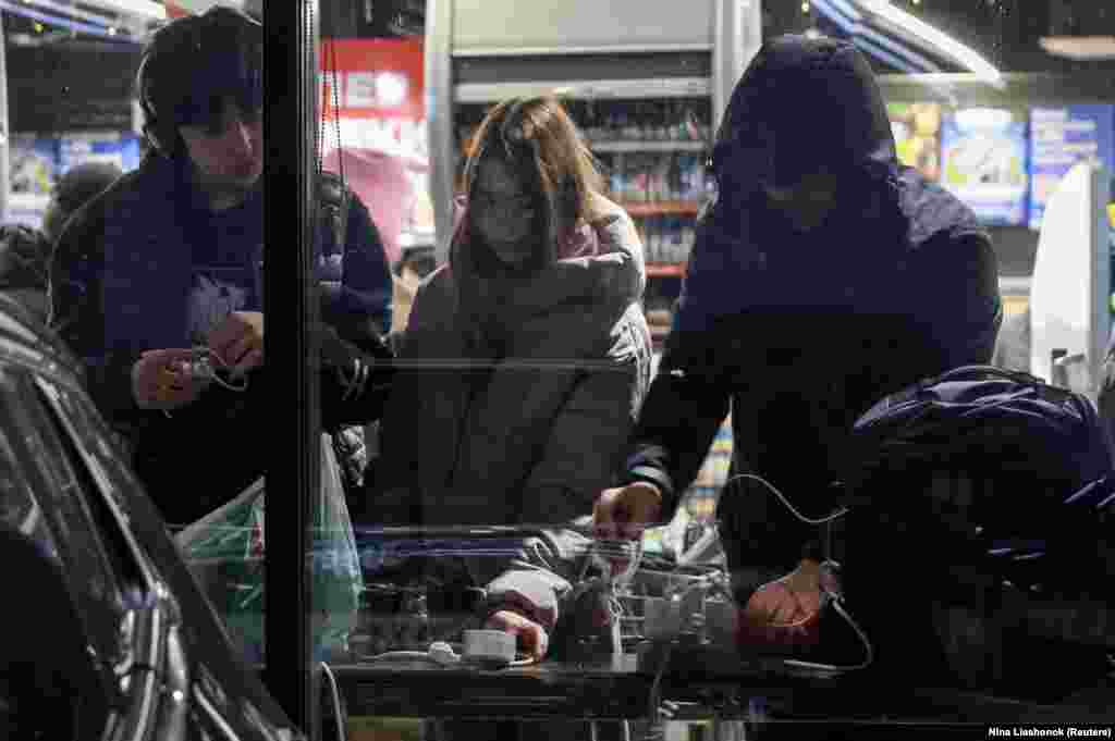 Жителі Одеси заряджають свої гаджети в одному з магазинів, які працюють на генераторах, під час відключення електроенергії. Одеса, 13 грудня 2025 року.Влада повідомила, що внаслідок нещодавніх російських атак по Одесі постраждала критично важлива цивільна інфраструктура міста. У більшості Одеси немає елекроенергії та водопостачання