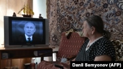 Илустрација - Повозрасна жена го гледа Путин на ТВ во Ставропол