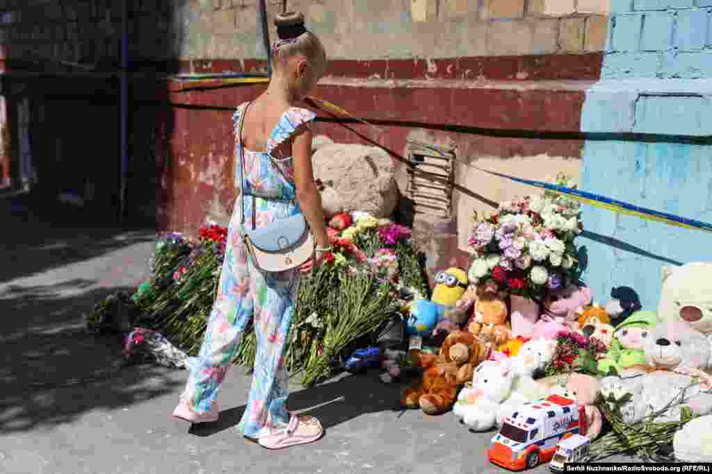 Дзеці нясуць кветкі і цацкі да жылога пяціпавярховіка ў Кіеве, у які трапіла расейская ракета. Расейская атака забрала жыцьці больш за 20 жыхароў гэтага дому, у тым ліку чатырох дзяцей. Жнівень 2025 году