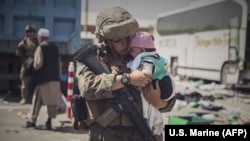 Кабул эл аралык аэропортундагы АКШ аскери ата-энеси текшерүүдөн өтүп жаткан баланы сооротууда. 30-август, 2021-жыл. 