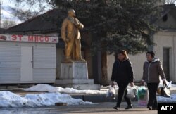 Жени вървят край статуя на Ленин в град Орловка, на 90 км от Бишкек, 11 март 2025 г.