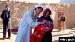 یو روغتیايي کارکوونکی یوې ماشومې ته د ګوزڼ واکسیني څاڅکي ورکوي او پولیس یې امنیت ته ولاړ دی - پخوانی انځور.