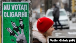 Un copil trecând pe lângă un poster electoral înfățișându-i pe Igor Dodon, Ilan Șor și Pavel Filip, la Chișinău, înaintea alegerilor parlamentare din februarie 2019