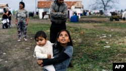 A Romany girl carries her brother on a street in the Bulgarian village of Ekzarh Antimovo.