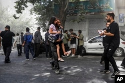 A man rushes a wounded girl away from the site of an explosion in Tehran amid Israeli strikes on the Iranian capital on June 15.