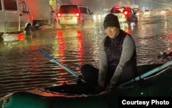 Болот Ибрагимов на надувной лодке в крупной луже на дороге в Бишкеке