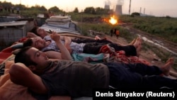 18 июля 2011 года. Таджикские трудовые мигранты после рабочего дня на одом из московских рынков отдыхают на крыше дома 