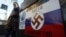 Дівчина проходить повз плакат із нацистською свастикою на російському прапорі та написом «Кольори окупантів» у столиці України. Київ, майдан Незалежності, 12 березня 2014 року