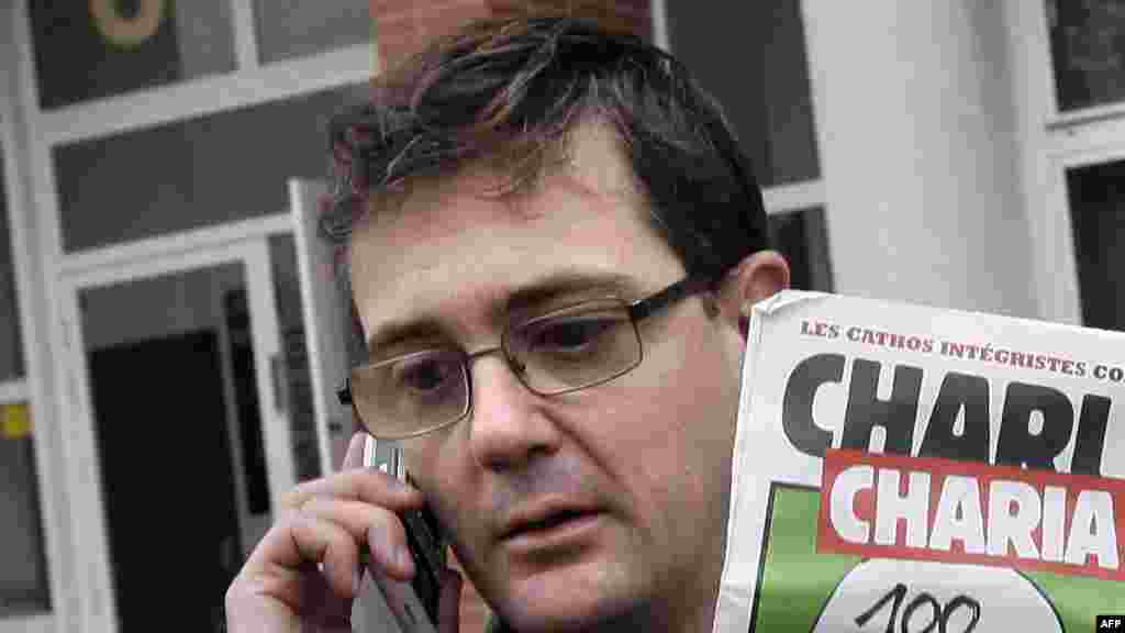 Charlie Hebdo's publisher, known only as Charb, uses his cell phone as he shows a special edition of the magazine in Paris on November 2, 2011.