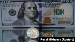 Монеты номиналом 200 тенге на фоне стодолларовой банкноты. Иллюстративное фото