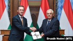 Varga Mihály pénzügyminiszter (b) átadja a 2025-ös költségvetés tervezetét Latorcai Jánosnak, az Országgyűlés KDNP-s alelnökének a Parlamentben 2024. november 11-én