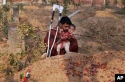 د پنجاب د ګوجراوالې اوسېدونکی محمد توفیق له خپل ۱۰ میاشتنۍ لور سره د ښځې قبر ته ناست دی. پولیس وايي د توفیق مور خپله نږور د "ناموس په نوم" وژلې وه - د ۲۰۱۶ز کال د جون ۱۸مې انځور.